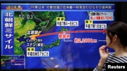 Prolaznica baca pogled na TV ektran i vest o severnokorejskom lansiranju rakete u Tokiju, Japan, 15. septembra 2017.