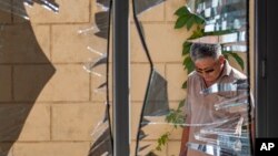 FILE - A Chinese Embassy employee examines broken windows at the embassy after a suicide bombing in Bishkek, Kyrgyzstan, Aug. 30, 2016. The bombing highlighted the expanding threat of an ethnic Uighur militant group that has sought for decades to establish an independent state in China’s far west for the repressed Muslim Uighur minority.