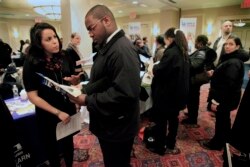 Daniela Silvero, left, an admissions officer at ASA College, discusses job opportunities with Patrick Rosarie, who is seeking a job in IT, during JobEXPO's 2012 job fair in New York.