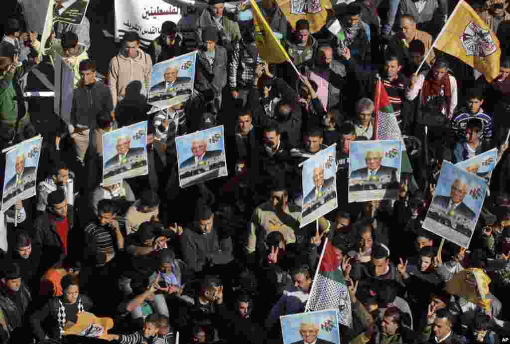 Palestinians hold pictures of President Mahmoud Abbas and wave Fatah flags during a rally supporting the Palestinian U.N. bid for observer state status, Nablus, occupied West Bank, November 29, 2012. 