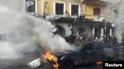 People gather near a burning car at the site of an explosion in the Shi'ite town of Hermel, Jan. 16, 2014. 