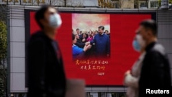 戴著口罩的行人走過上海街頭宣傳習近平的宣傳畫。（2020年3月23日）
