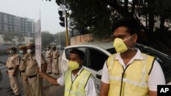 Volunteers and policemen wear pollution masks and stand at a busy crossing with the banner saying obey odd and even, remove pollution, in New Delhi, India, Nov. 4, 2019.