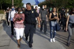 El jefe de policía de Houston, Art Acevedo, camina del brazo de una mujer afroestadounidense durante un evento en se reclamó "Justicia para George Floyd" en Houston, Texas, el 30 de mayo de 2020.