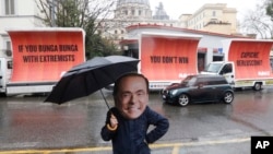An actor wearing a mask depicting former Italian premier Silvio Berlusconi performs alongside billboards March 5, 2018, in Rome. The billboards were organised by the global civic movement Avaaz as a reaction to the right-wing coalition not reaching a majo