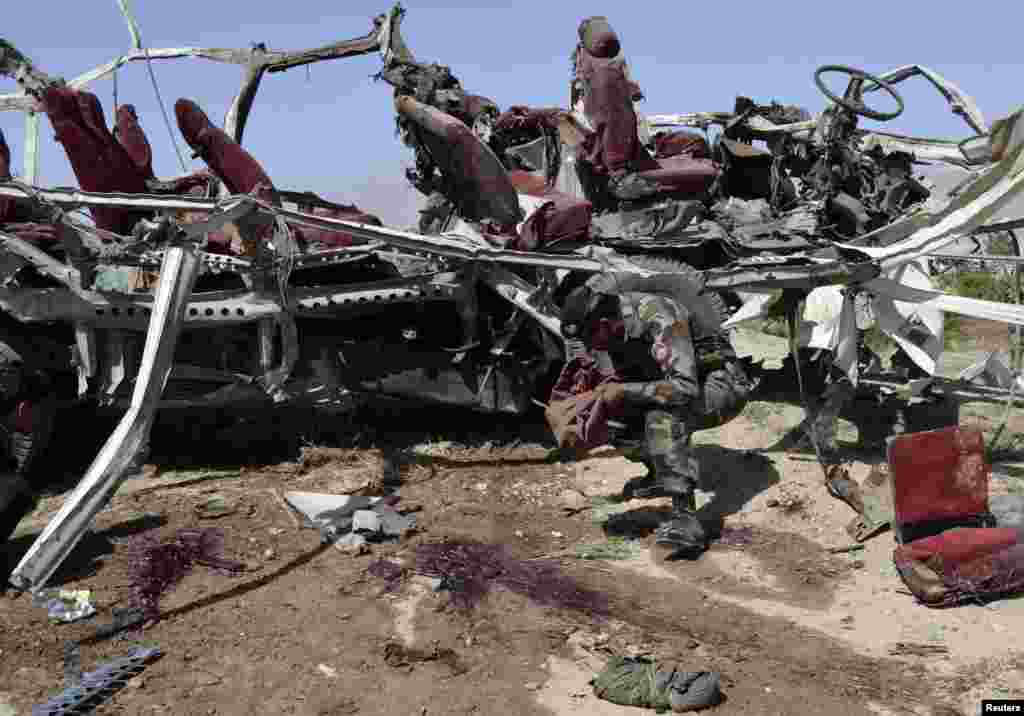 A security official collects evidence near the remains of a damaged vehicle at the site of a bomb blast in Quetta, Pakistan, May 23, 2013.