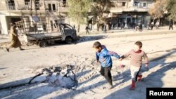 Boys run near a hole in the ground after airstrikes by pro-Syrian government forces in the rebel-held al-Sakhour neighborhood of Aleppo, Syria, Feb. 8, 2016. 