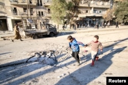 Boys run near a hole in the ground after airstrikes by pro-Syrian government forces in the rebel-held al-Sakhour neighborhood of Aleppo, Syria, Feb. 8, 2016.