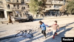Boys run near a hole in the ground after airstrikes by pro-Syrian government forces in the rebel-held al-Sakhour neighborhood of Aleppo, Syria, Feb. 8, 2016.