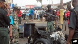 Security personnel inspect the mangled remains of bomb-laden car that exploded along junction road near a church, Kaduna, Nigeria, April 8, 2012.