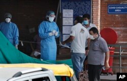Keluarga pasien menanyakan perkembangan kondisi pasien Covid-19 dari petugas medis di sebuah rumah sakit khusus di New Delhi, India, 10 Jini 2020. (Foto: dok).