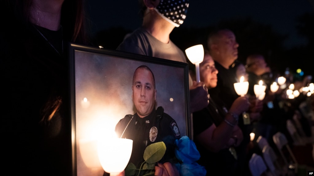 FILE - A woman holds a candle and a picture of a fallen police officer during the National Law Enforcement Officers Memorial Fund's Annual Candlelight Vigil, on the National Mall, in Washington., Oct. 14, 2021.
