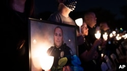 FILE - A woman holds a candle and a picture of a fallen police officer during the National Law Enforcement Officers Memorial Fund's Annual Candlelight Vigil, on the National Mall, in Washington., Oct. 14, 2021.