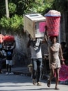 FILE - People carry their belongings along a street as they flee their homes from gang violence, in Port-au-Prince, Haiti, Oct. 26, 2024.