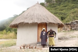 Praxedes Chadambura with her mother-in-law in front of her new thatched hamlet.