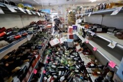 Bottles of wine are strewn in the middle of an aisle as Victor Abdullatif, background center, mops inside of the Eastridge Market, his family's store, July 6, 2019, in Ridgecrest, Calif.