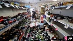 Bottles of wine are strewn in the middle of an aisle as Victor Abdullatif, background center, mops inside of the Eastridge Market, his family's store, Saturday, July 6, 2019, in Ridgecrest, Calif. Crews in Southern California assessed damage to…