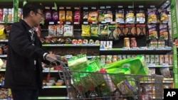 Un bărbat împinge un coș de cumpărături pe lângă un afișaj de nuci importate din Statele Unite și alte țări la un supermarket din Beijing, luni, 2 aprilie 2018. (AP Photo/Andy Wong)