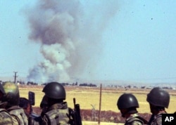 FILE - Turkish soldiers watch smoke billow from the Syrian town of Kobani following the attacks by IS militants as seen from the Turkish side of the border in Suruc, June 25, 2015.