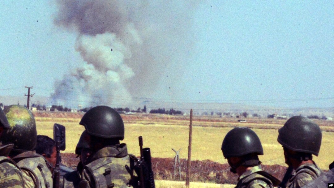 Turkish soldiers watch smoke billow from the Syrian town of Kobani following the attacks by IS militants as seen from the Turkish side of the border in Suruc, June 25, 2015.