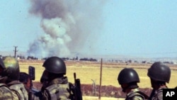 Turkish soldiers watch smoke billow from the Syrian town of Kobani following the attacks by IS militants as seen from the Turkish side of the border in Suruc, June 25, 2015.