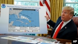 President Donald Trump talks with reporters after receiving a briefing on Hurricane Dorian in the Oval Office of the White House, in Washington, Sept. 4, 2019. The projected path of the hurricane appears to have been extended with a black felt marker.