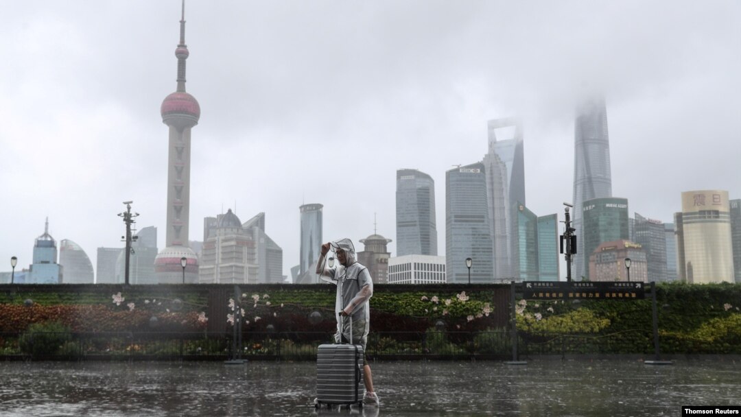 台风“烟花”正在逼近上海，一位男子冒雨走在黄浦江边的外滩。（路透社照片）
