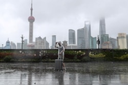 颱風“煙花”正在逼近上海，一位男子冒雨走在黃浦江邊的外灘。 （路透社照片）