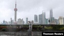台风“烟花”正在逼近上海，一位男子冒雨走在黄浦江边的外滩。（路透社照片）