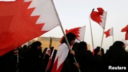 FILE - Opposition protesters, holding Bahraini flags, are seen during an anti-government rally in Sitra, south of Manama, June 28, 2013.