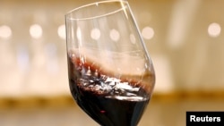 FILE - A sommelier shakes a glass of Brunello di Montalcino's Marchesi Frescobaldi red wine at the 50th Vinitaly international wine and spirits exhibition in Verona, northern Italy, April 12, 2016. 