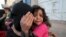 FILE - A girl cries next to her mother covering her face as they flee from an airstrike on an army weapons depot in Yemen's capital Sanaa.