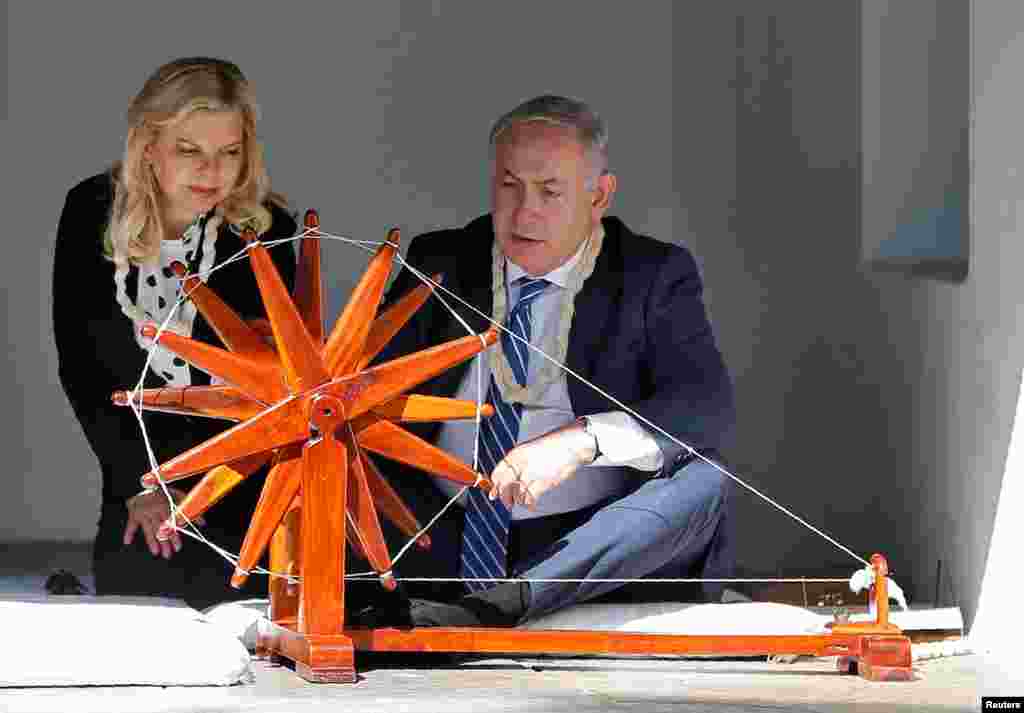 Israeli Prime Minister Benjamin Netanyahu spins cotton on a wheel as his wife Sara looks on during their visit to Gandhi Ashram in Ahmedabad, India.