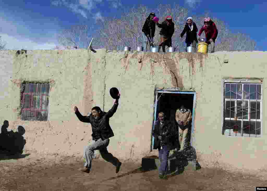 Perempuan Tadjik menyiram air ke para pria ketika mereka ikut berpartisipasi untuk menyambut datangnya Musim Semi di daerah otonomi Tadjik, Kashgar, Wilayah Otonomi Uighur Xinjiang , China, 18 Maret 2015.