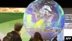 FILE - People watch the Earth globe at the COP21, the United Nations conference on climate change in Le Bourget, Dec. 10, 2015. 
