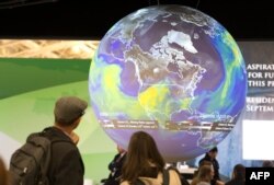 People watch the Earth globe at the COP21, the United Nations conference on climate change in Le Bourget, Dec. 10, 2015.