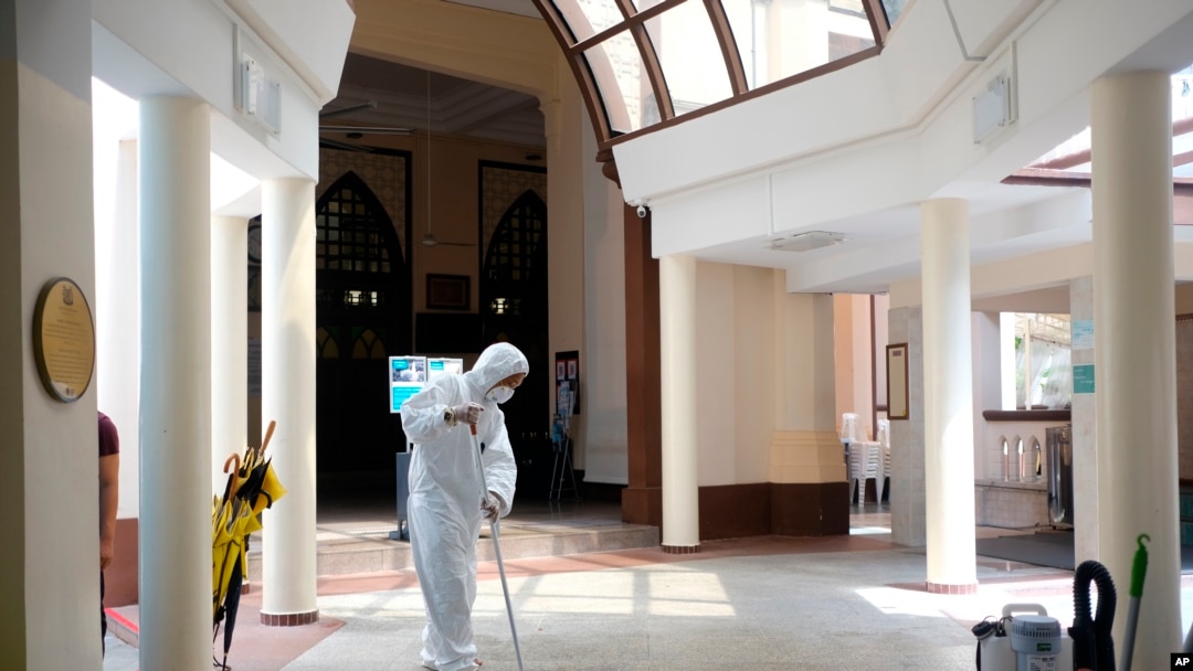 A man wearing protective suit and mask mops the floor inside the Hajjah Fatimah mosque, in Singapore, March 13, 2020.