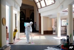 A man wearing protective suit and mask mops the floor inside the Hajjah Fatimah mosque, in Singapore, March 13, 2020.