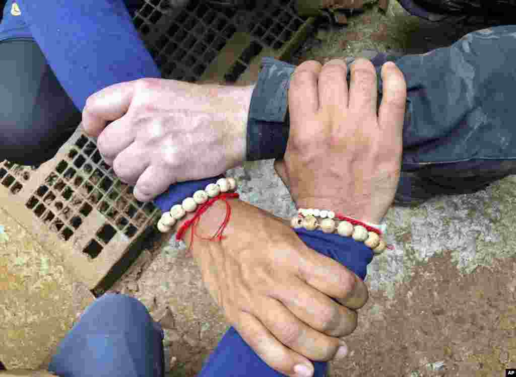 This undated photo released via the Thailand Navy SEAL Facebook page July 8, 2018, shows rescuers hands locked with a caption reading &quot;We Thai and the international teams join forces to bring the young Wild Boars home.&quot;