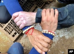This undated photo released via the Thailand Navy SEAL Facebook page on Sunday, July 8, 2018, shows rescuers hands locked with a caption reading "We Thai and the international teams join forces to bring the young Wild Boars home."
