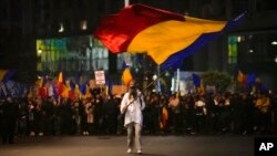 A man waves a flag outside Romania's government headquarters during an anti-government and anti-restrictions protest organized by the far-right Alliance for the Unity of Romanians, in Bucharest, Romania, Oct. 2, 2021.