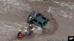 This drone image provided by the Golder Ranch Fire District shows firefighters safely rescue a man and his two daughters from the roof of their vehicle after it was swept away in fast-moving water just north of Tucson, Ariz., on July 14, 2021.