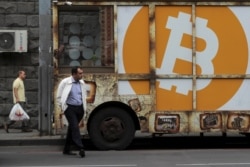 FILE - People walk past a board with the logo of Bitcoin in a street in Yerevan, Armenia September 9, 2019. REUTERS/Anton Vaganov