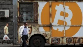 FILE - People walk past a board with the logo of Bitcoin in a street in Yerevan, Armenia September 9, 2019. REUTERS/Anton Vaganov
