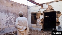 Hajj Ahmed, um residente do bairro de Old-Omdurman, olha para a sua casa depois de esta ter sido danificada por obuses em Omdurman. Fotografia de arquivo
