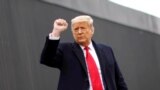 Donald Trump raises his fist as he visits the U.S.-Mexico border wall,