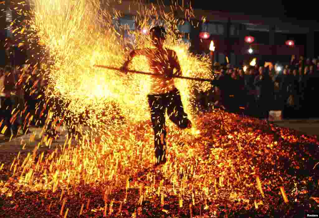 A man walks through burning charcoal as he participates in the traditional ritual called &quot;Lianhuo&quot;, or &quot;fire walking&quot;, in Pan&#39;an county, Zhejiang province, China, Nov. 25, 2013. Dozens of men walk past burning charcoal or firewood barefooted, as a way to ward off evil and pray for good fortune in the local ritual.