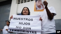 Dionexis García, hermana de Dioner Gómez, cuya fotografía muestra otro miembro de la familia, sostiene un cartel que dice en español "Nuestros hijos no son terroristas" afuera de un centro de detención, donde se encuentran algunos menores en Caracas.