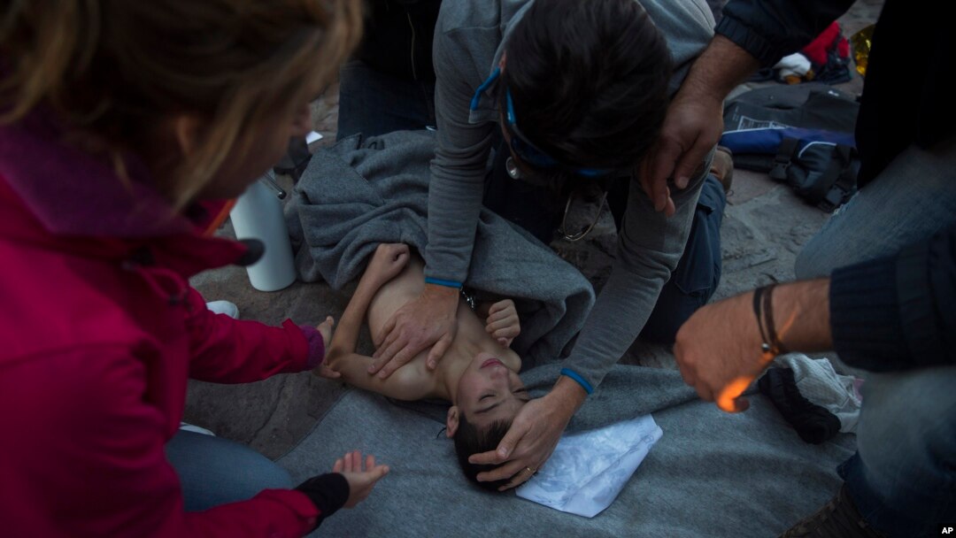 Petugas paramedik dan dokter merawat seorang anak laki-laki yang tenggelam dalam kapal pengungsi dan migran di Laut Aegea dari Turki ke Pulau Lesbos, Yunani (28/10). (AP/Santi Palacios)