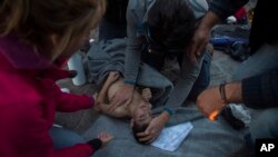 Petugas paramedik dan dokter merawat seorang anak laki-laki yang tenggelam dalam kapal pengungsi dan migran di Laut Aegea dari Turki ke Pulau Lesbos, Yunani (28/10). (AP/Santi Palacios)